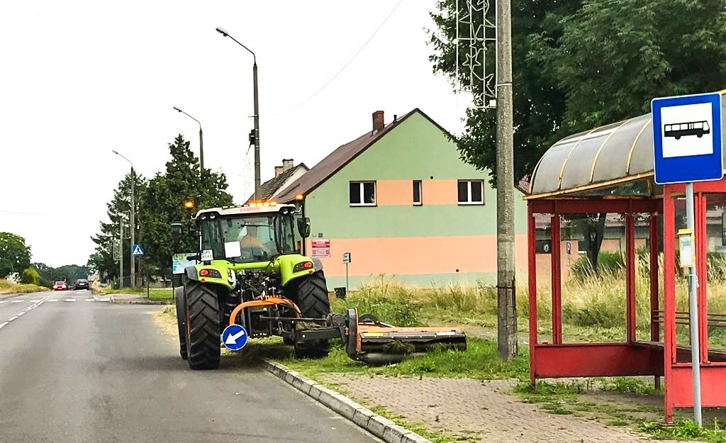 Traktor wykaszający pobocza w rejonie przystanku autobusowego w Woli.