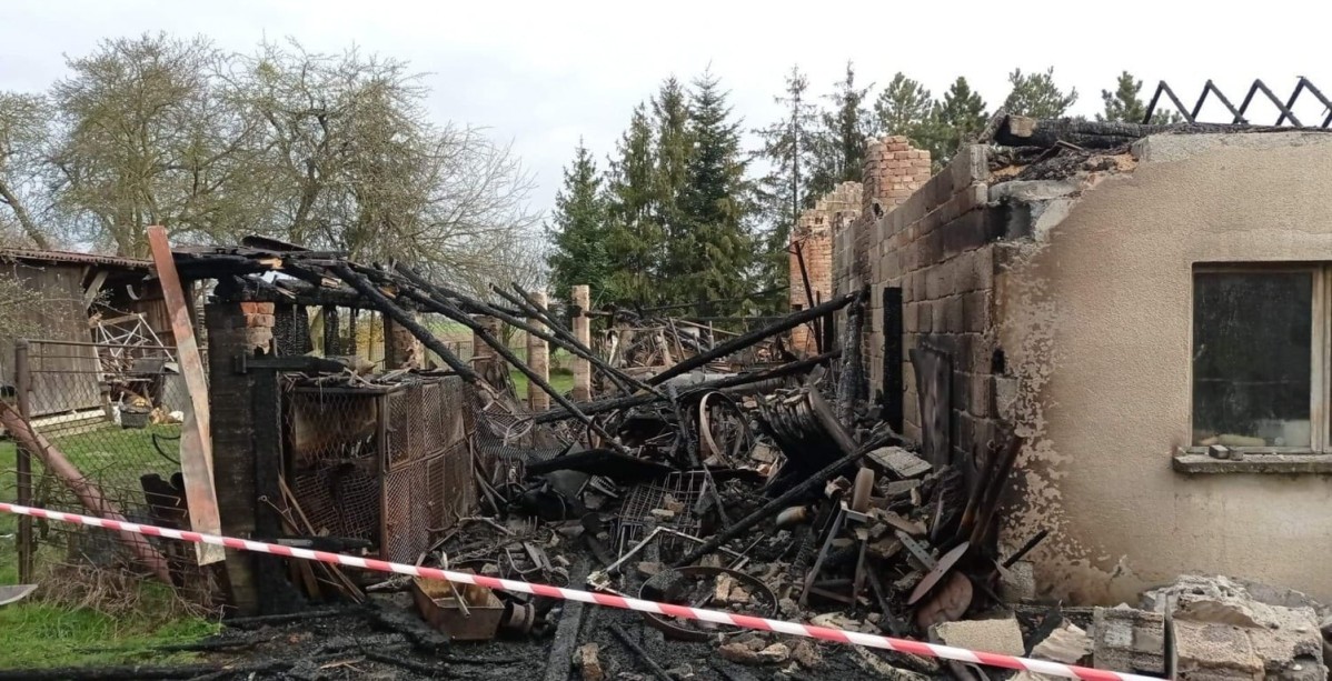 Budynek po pożarze, bez dachu. Obok leżą spalone przedmioty.