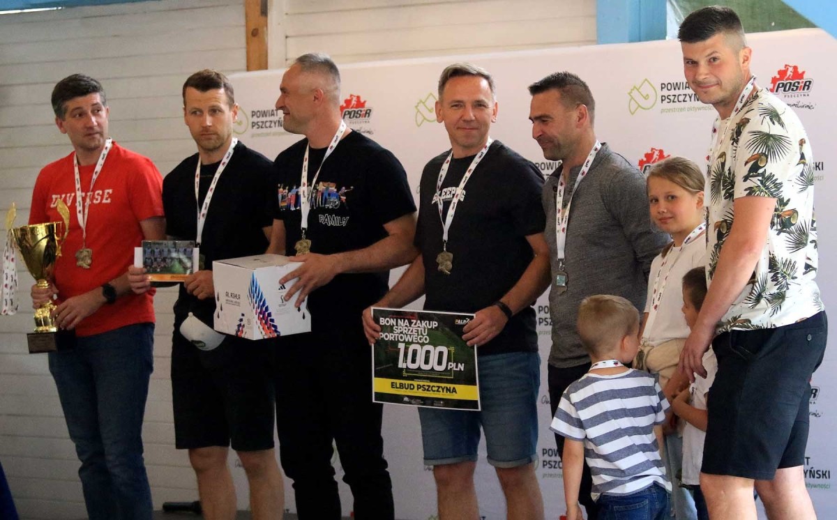 gRUPA PIŁKARZY STOI NA PODIUM. tRZYMAJA PUCHAR