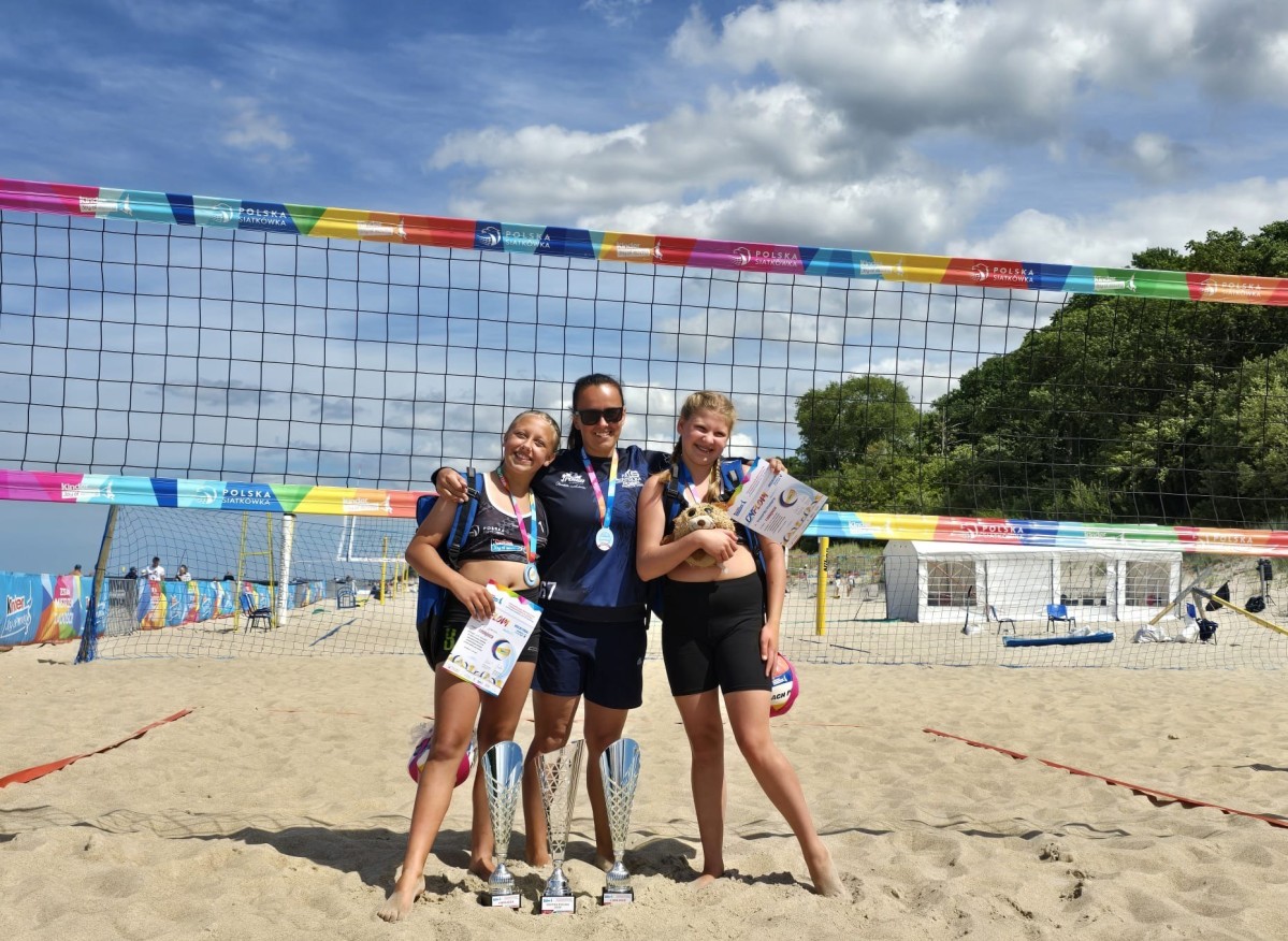Siatkarki ze swoją trenerką na boisku do piłki plażowej.