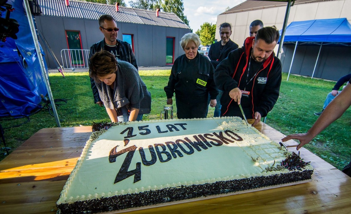 Cztery osoby kroją wielki tort z napisem Żubrowisko 15 lat