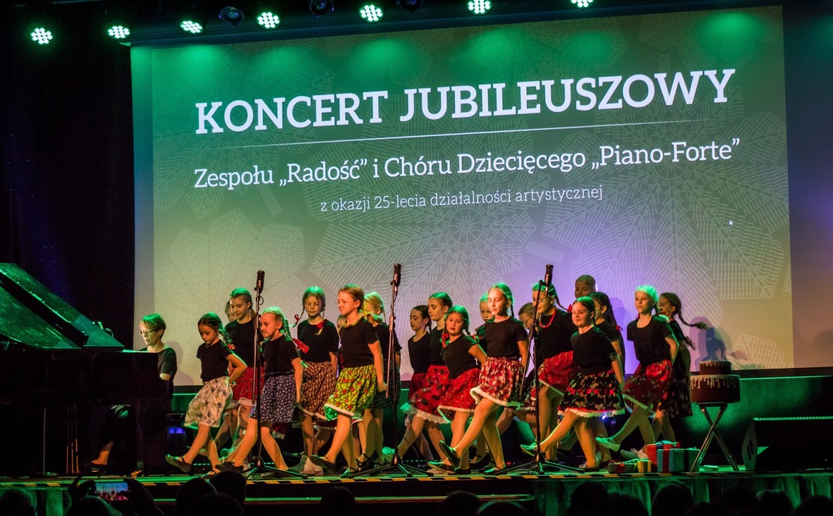 Dzieci w kolorowych strojach regionalnych występują na scenie.
