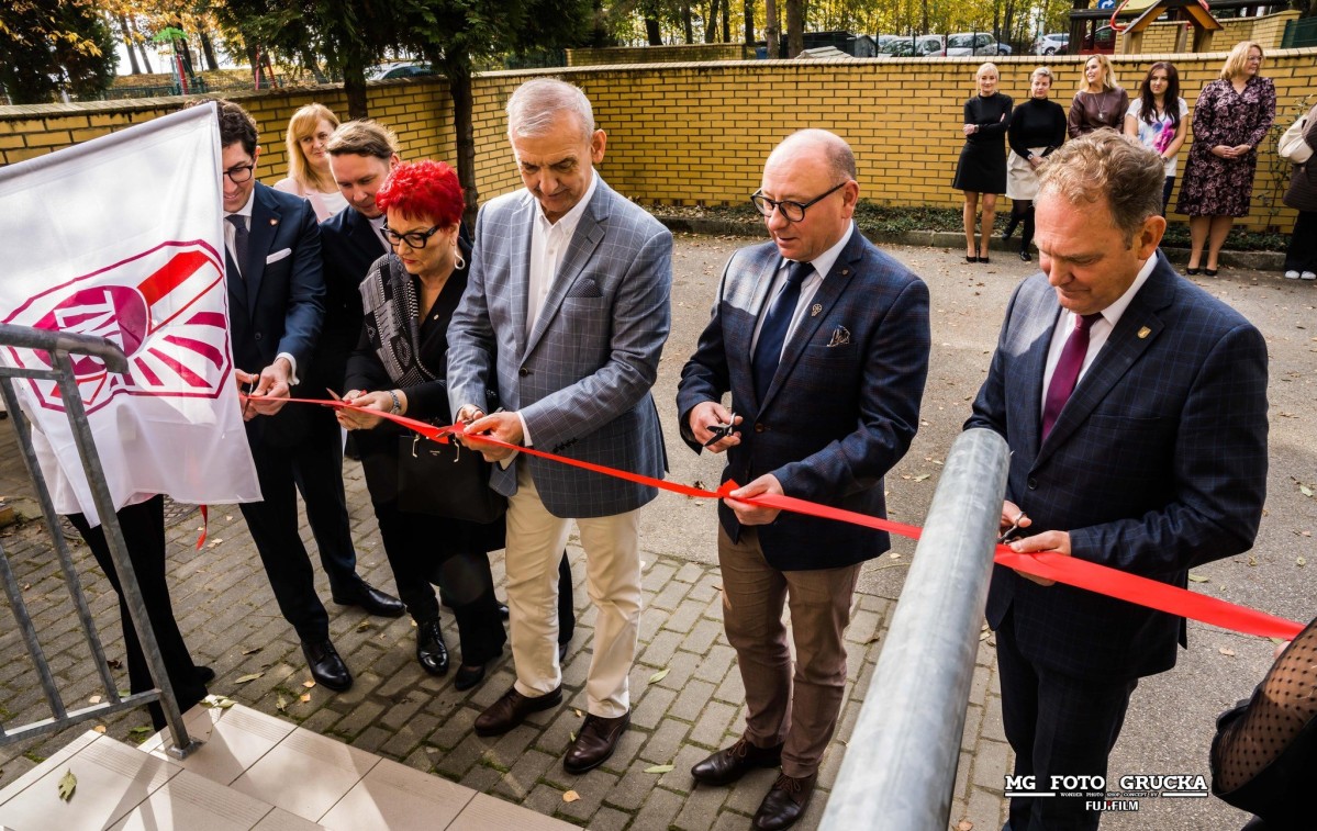 Goście przecinają czerwoną wstęgę przed wejsciem do nowej siedziby związku