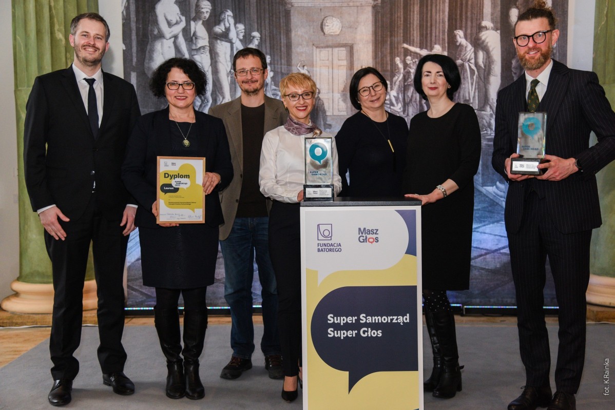 Przedstawiciele Pszczyna Miasto Zielone i Powiatu oraz Fundacji Batorego i Masz Głos, stoją przy mównicy z nagrodami.