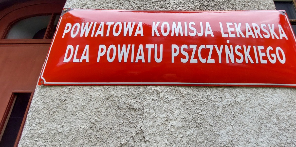 Tablica czerwona z napisem: Powiatowa Komisja Lekarska dla powiatu pszczyńskiego.