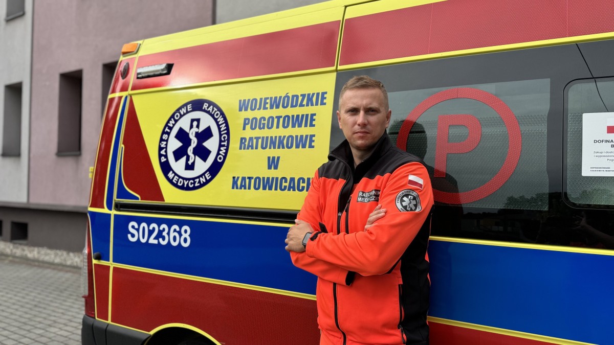 Ratownik medyczny stoi na tle karetki pogotowia