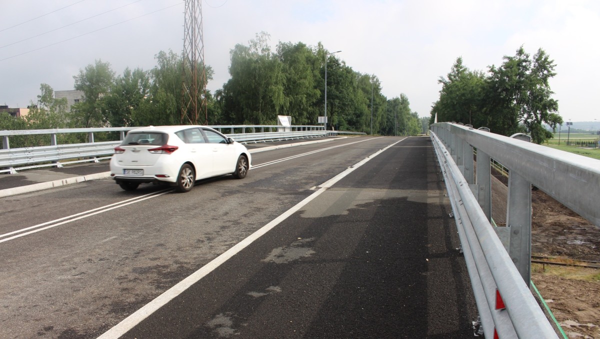 Nawierzchnia wyremontowanej drogi, po której jedzie biały samochód osobowy.