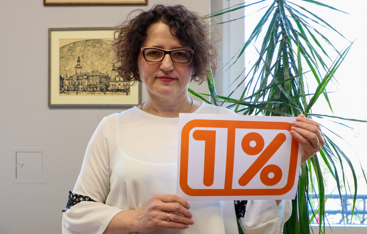 Starosta Barbara Bandoła zachęca do przekazania 1% podatku OPP w powiecie pszczyńskim, trzymając kartkę z pomarańczowym napisem 1%