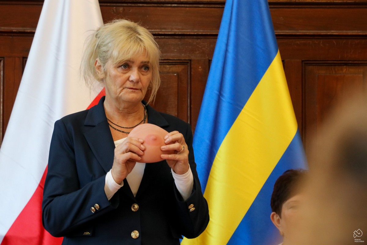 Kobieta trzyma w dłoni atrapę piersi.