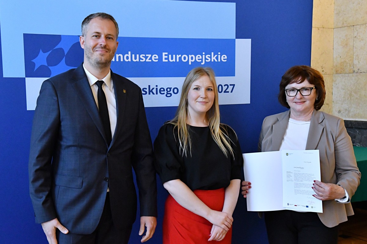 Pracownicy Starostwa z członkinią Zarządu Woj. Śląskiego, we wspólnym zdjęciu po odebraniu listu, który trzymają w dłoniach.