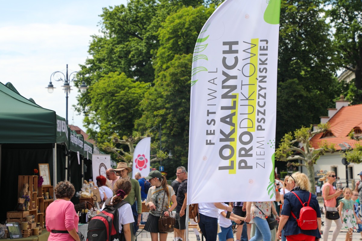 Odwiedzający przy stosikach, z przodu flaga festiwalu.
