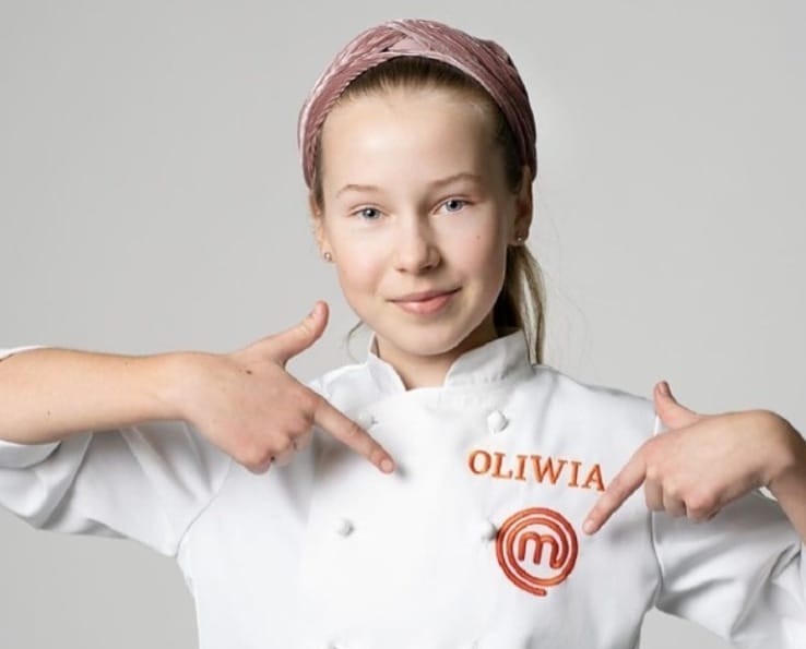 Oliwia Piech w białym fartuchu z logo MasterChef Junior.