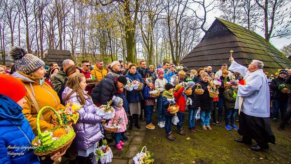 Ksiądz święcący pokarmy w koszyczkach, które trzymają licznie zgromadzeni ludzie.