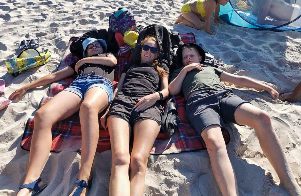 Dzieci leżą na plaży na piasku.