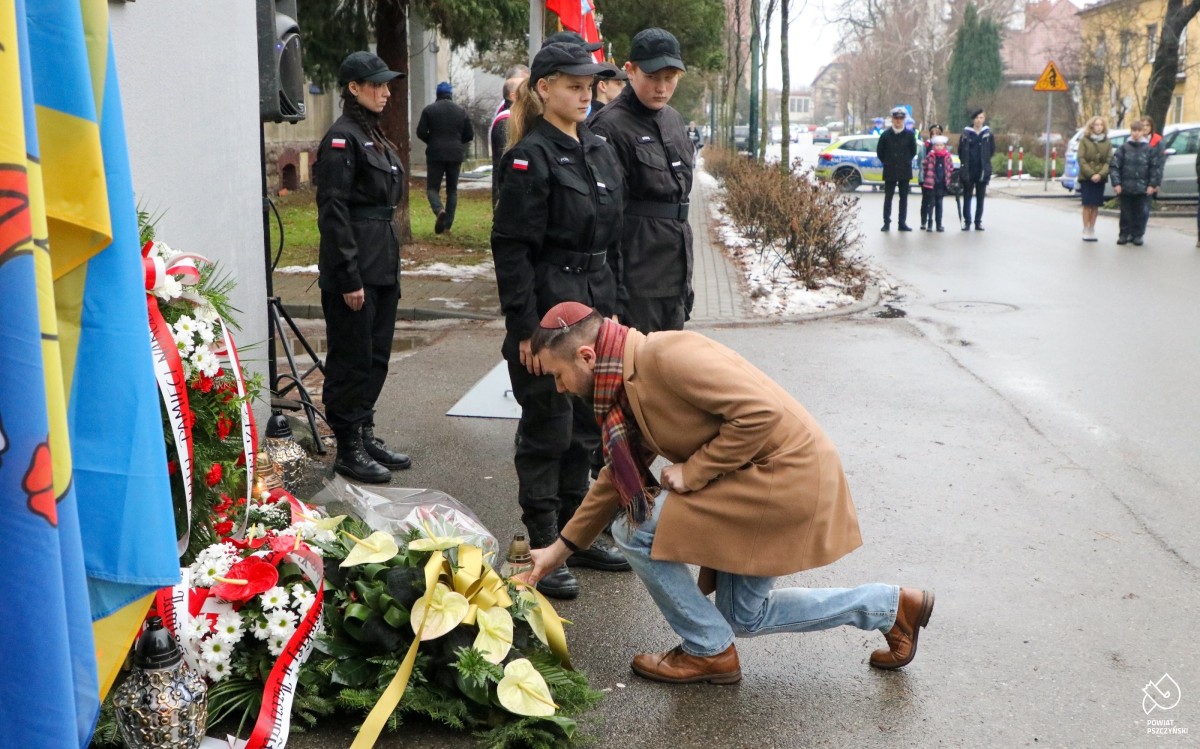 Sławomir Pastuszka składa znicz pod pomnikiem.