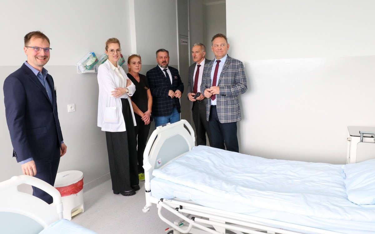 w sali pacjentów przy łóżku szpitalnym stojawłodarze oraz kadra medyczna szpitala.