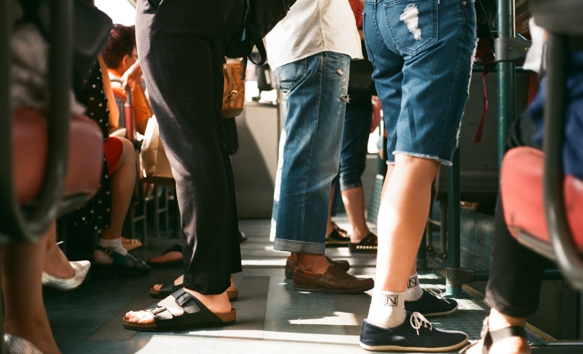 Nogi osób podróżujących autobusem. Stoją obok siebie w przedsionku.