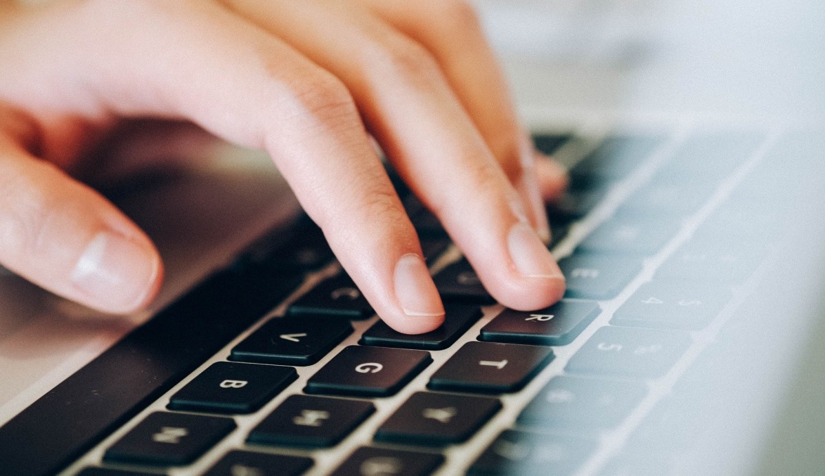 Dłonie położone na klawiaturze laptopa.
