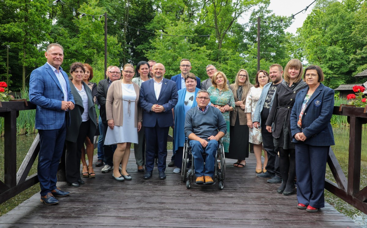 Rodziny zastępcze na pomoście w skansenie we wspólnym zdjęciu ze starostą.