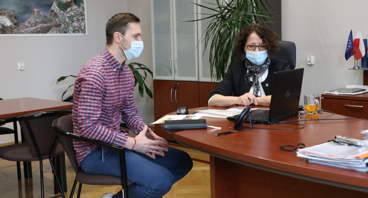 Michał Zioło i Barbara Bandoła siedzą za biurkiem przed laptopem podczas wideokonferencji.