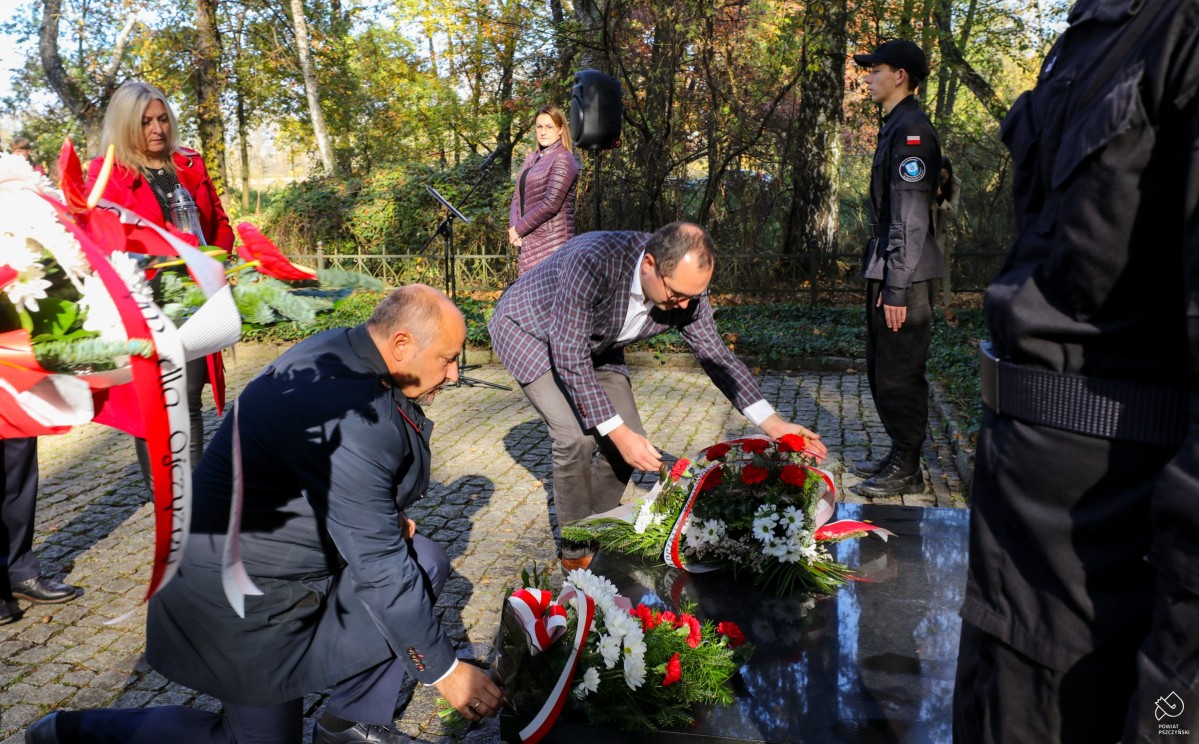 Starosta z wicewojewodą składają kwiaty na grobie na cmentarzu pod trzema dębami.