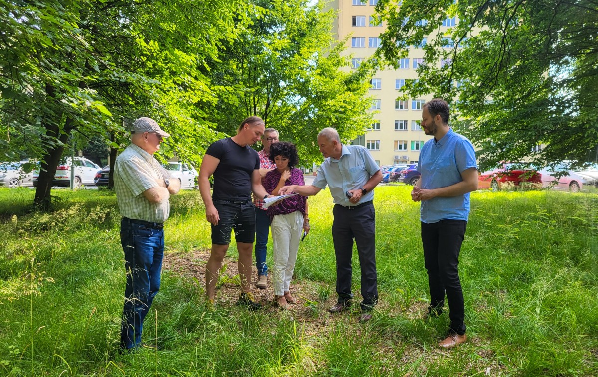Przedstawiciele wykonawcy, powiatu i projektantka stoją w miejscu zaplanowanej inwestycji i oglądają projekt.