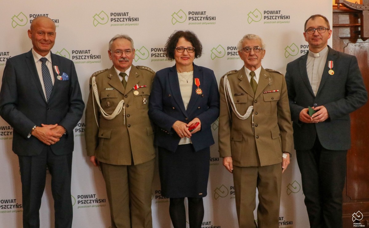 Odznaczeni wraz z byłymi żołnierzami na tle ścianki z logo powiatu pszczyńskiego.
