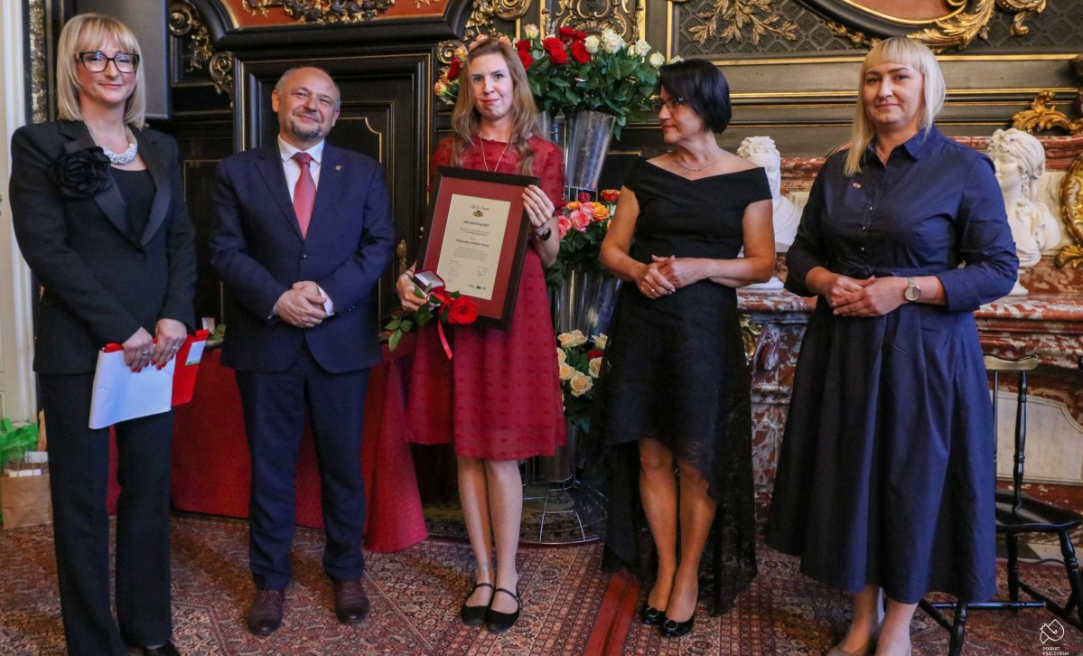 Aleksandra Kobiór Sosna ze starostą i innymi osobami wręczającymi odznaczenie