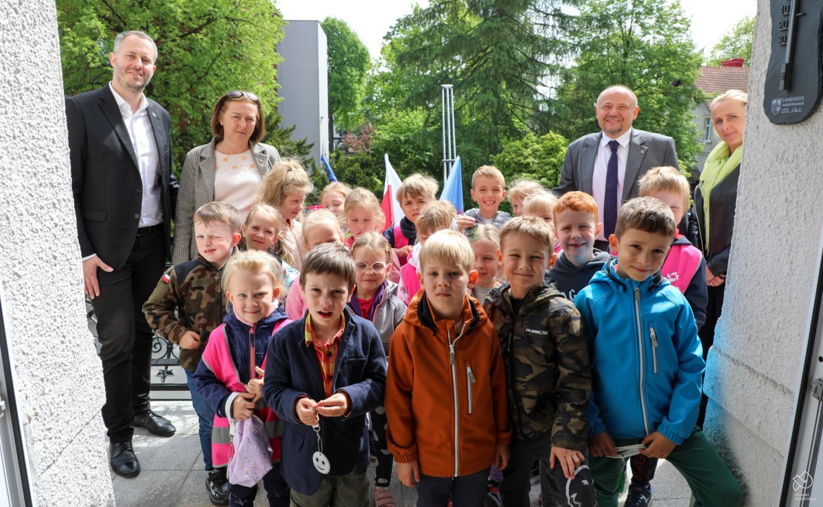 Przedszkolaki na balkonie, we wspólnym zdjęciu z wychowawcami i starostą.