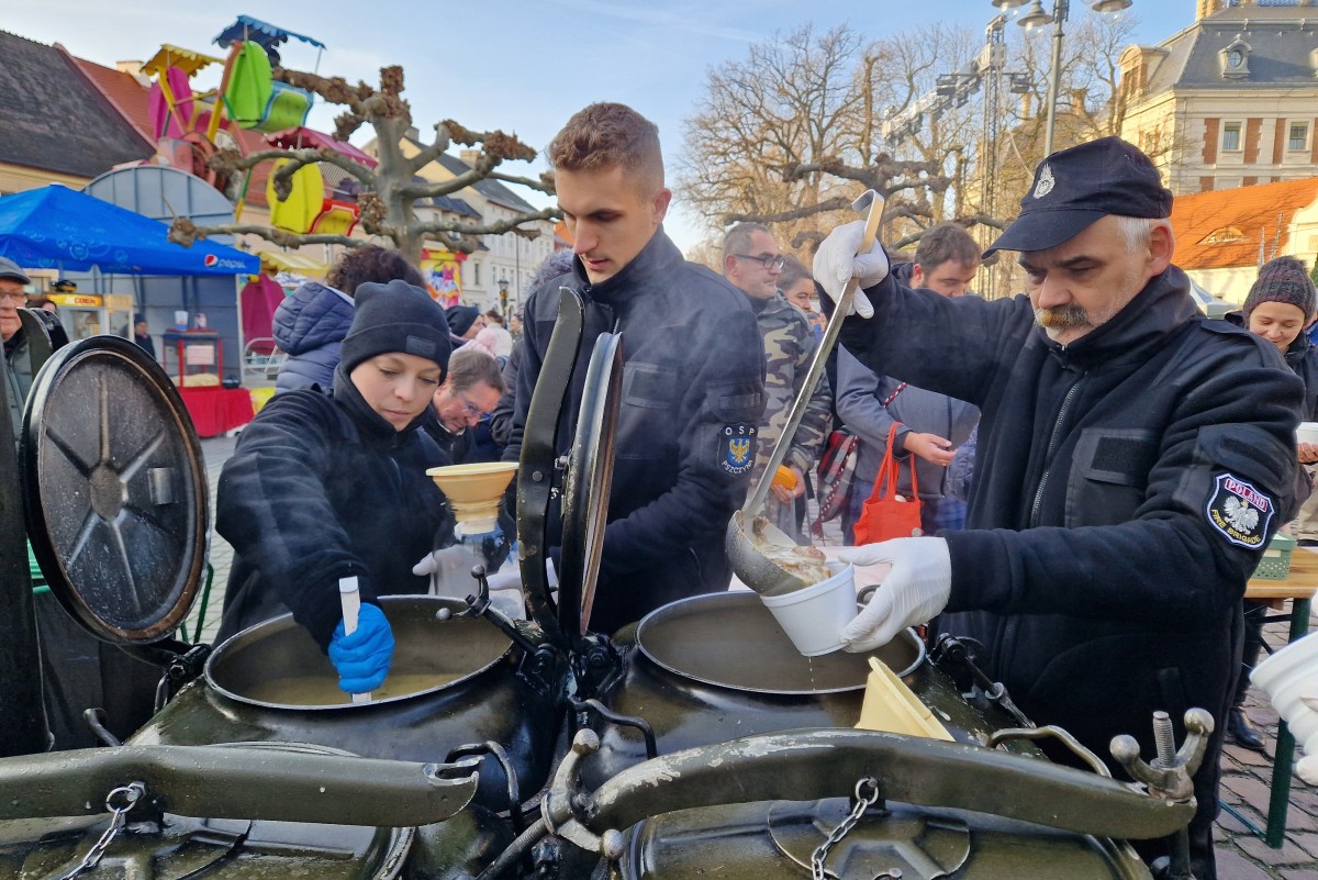 Strażacy nalewający zupę na rynku z dużych kotłów.