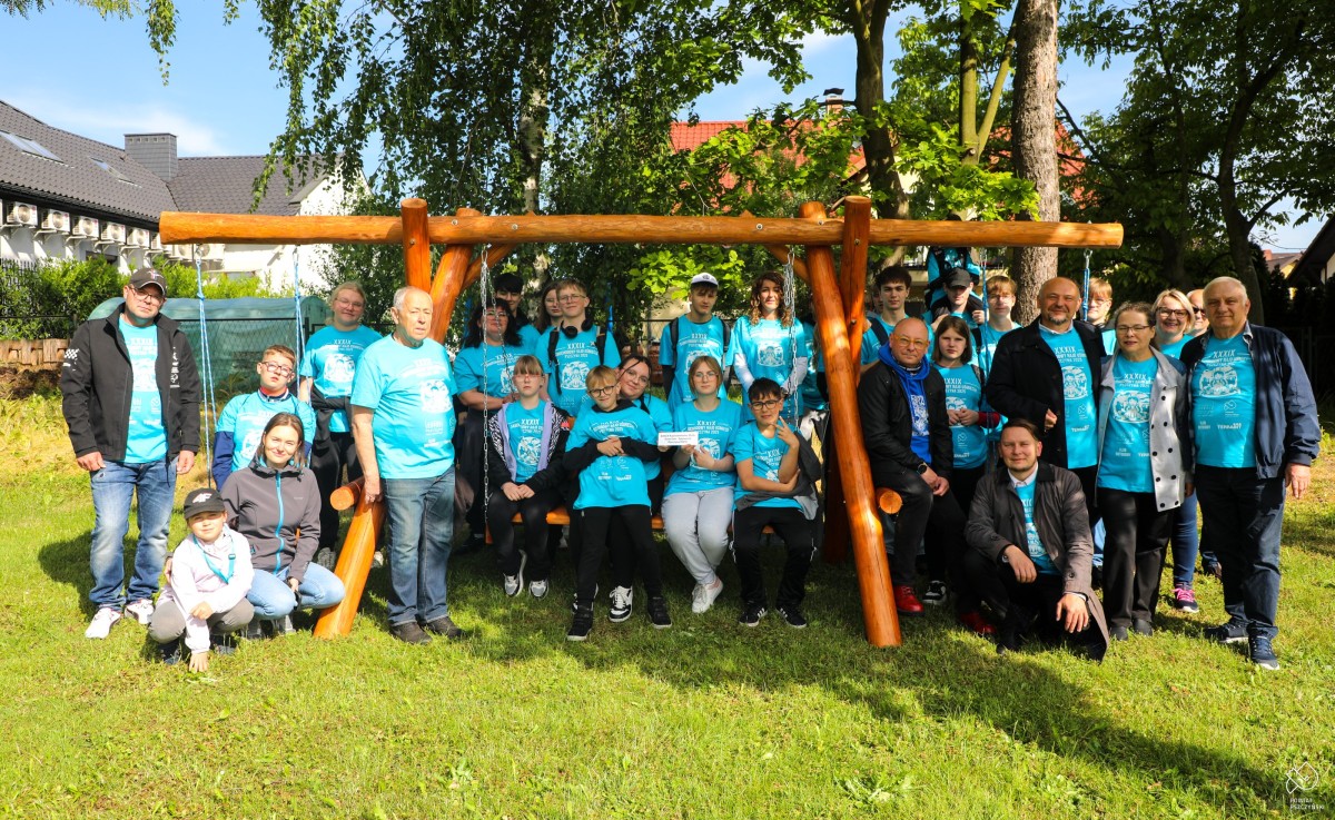 Samorządowcy, organizatorzy, sponsorzy z dziećmi na huśtawce, którą otrzymały.
