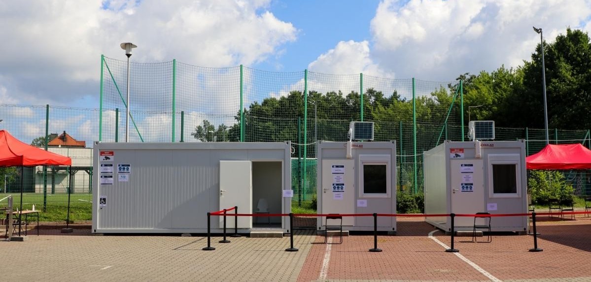 Na utwardzonym kostka brukowa terenie znajdują sie budynki modułowe, w których można szczepi się przeciwko COVID-19