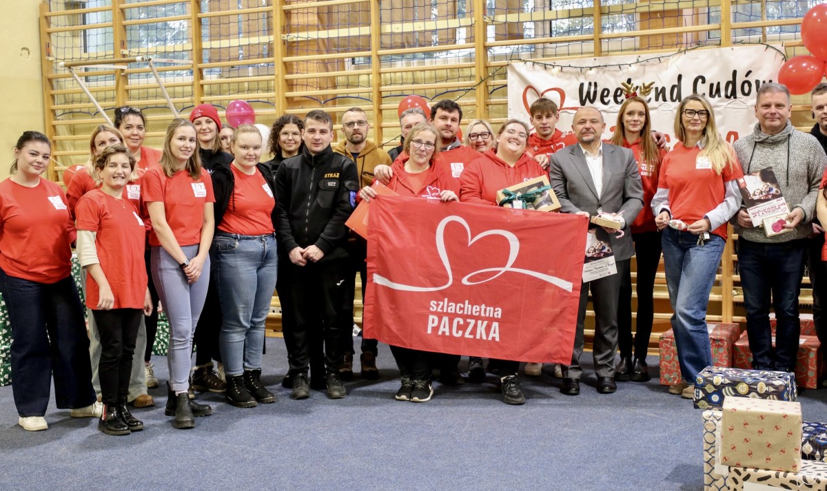Wolontariusze we wspólnym zdjęciu, trzymają flagę szlachetna paczka