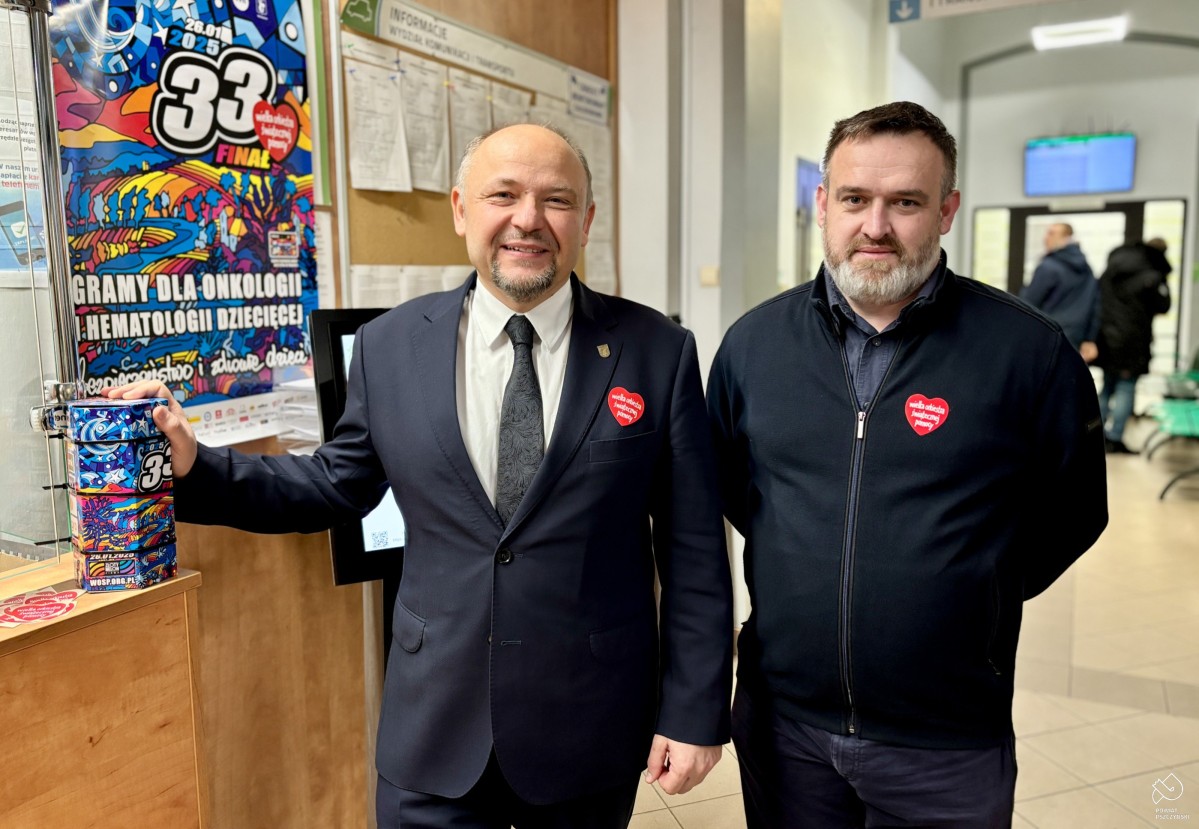 Starosta z szefem sztabu stoją na korytarzu starostwa, obok lady, na której umieszczona jest kolorowa puszka WOŚPu.