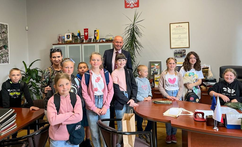 Grupa uczniów ze szkoły w Czrakowie pozuje do zdjęcia w gabinecie starosty razem z sekretarzem powiatu