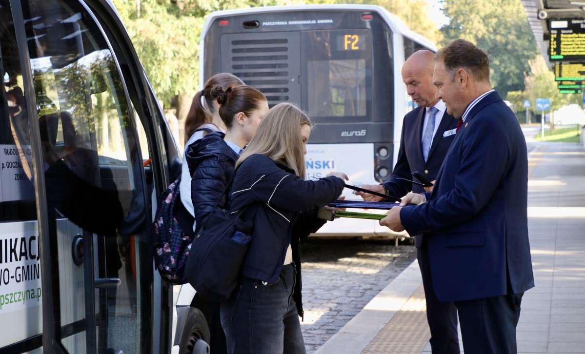 Wicestarosta i sekretarz rozdają odblaski wychodzącym z autobusu.