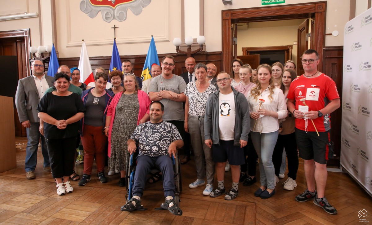 Podopieczni we wspólnym zdjęciu z pracownikami Starostwa w sali sesyjnej.