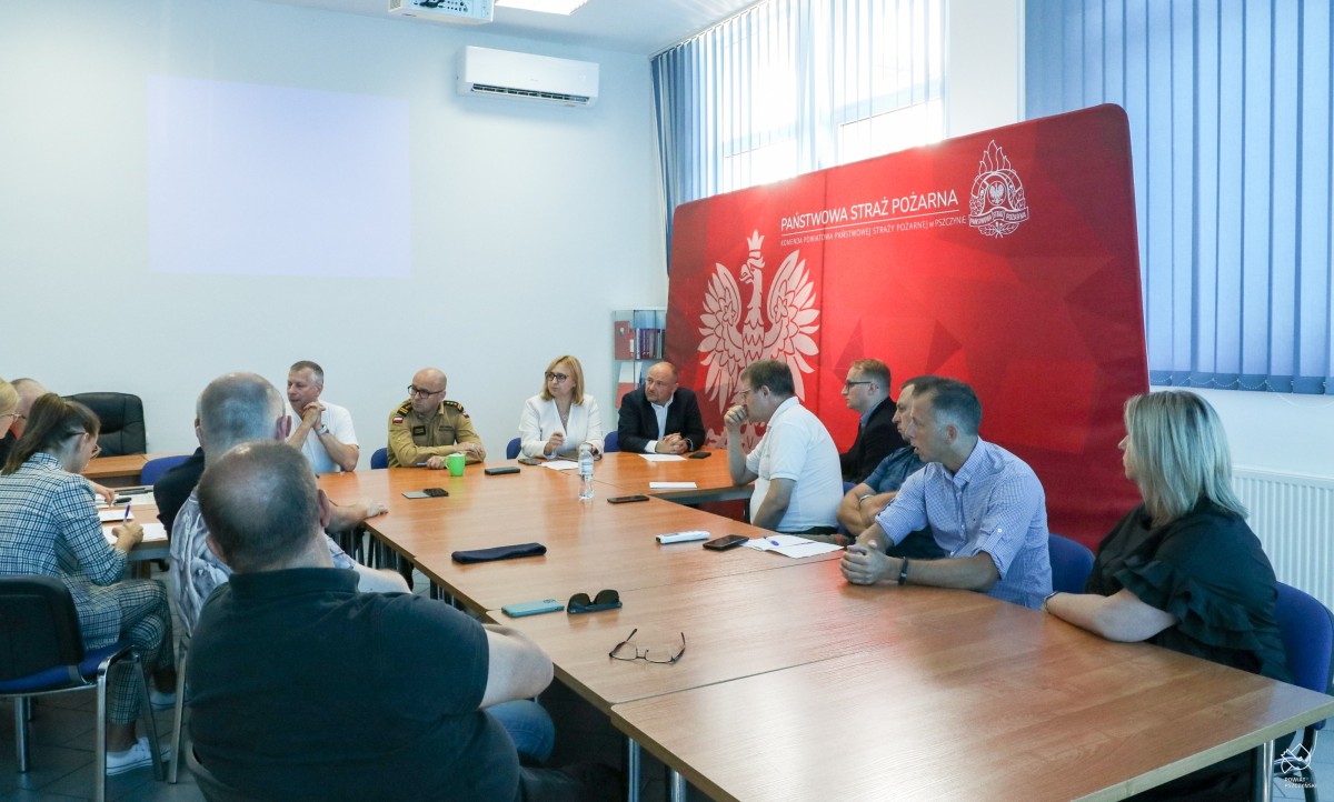 W salce komendy straży pożarnej za stołami siedzą przedstawiciele służb odpowiedzialnych za bezpieczeństwo