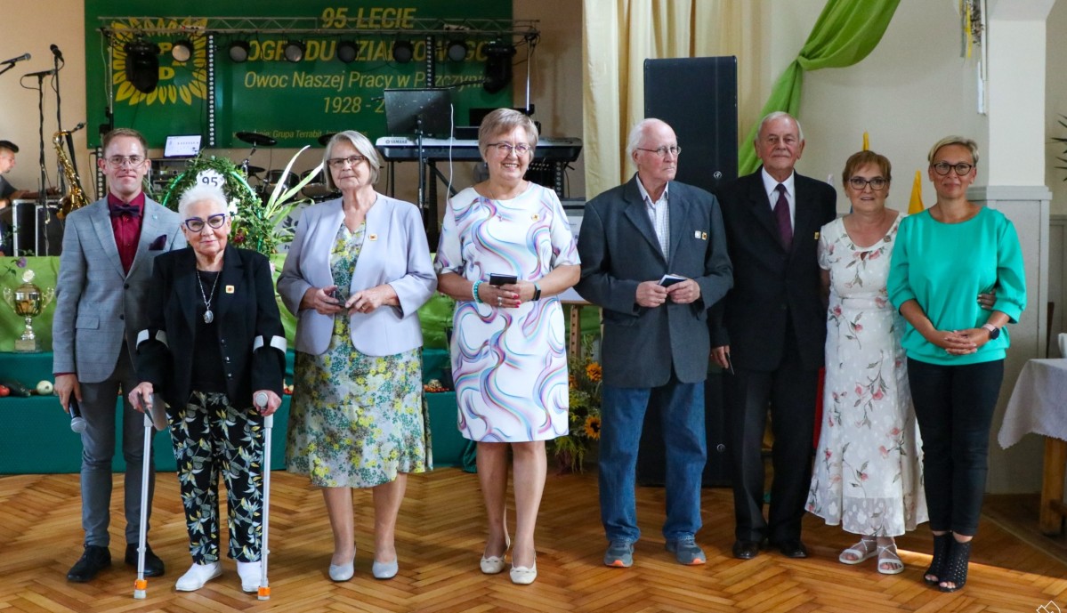 Działkowicze odznaczedni złotą odznaką stoją w domu działkowca i pozuja do zdjęcia