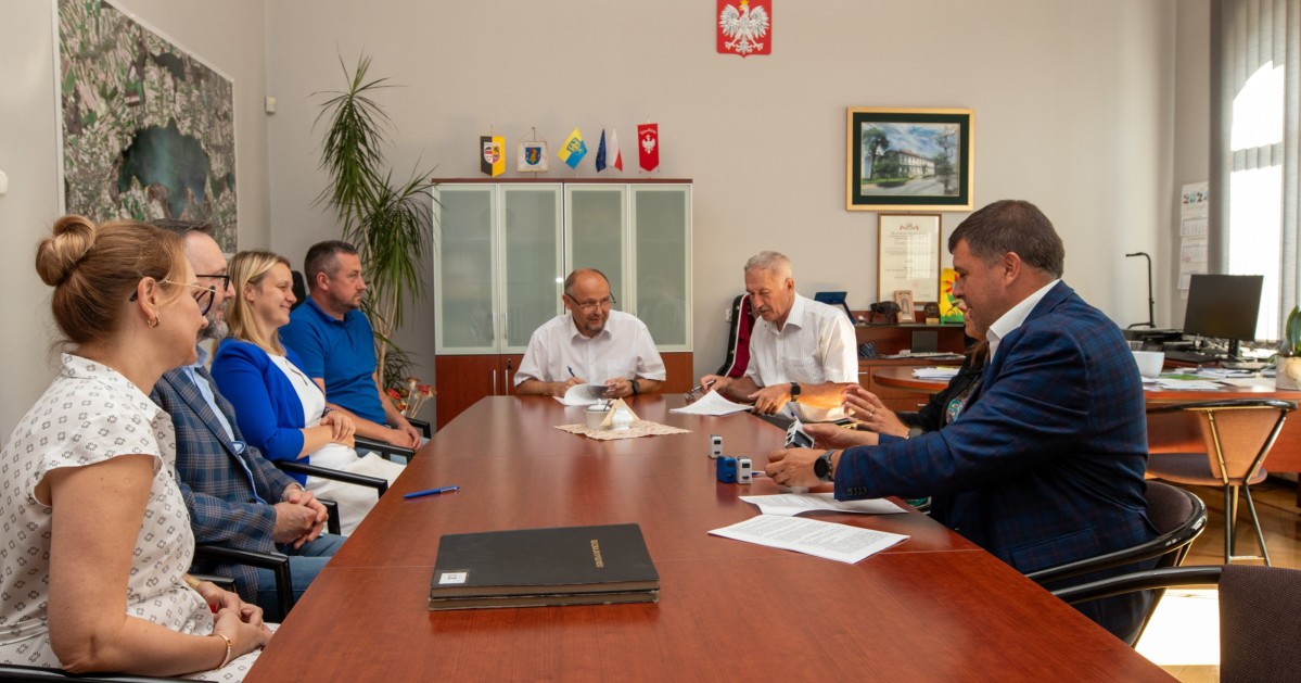 Uczestnicy spotkania podpisują umowę w gabinecie starosty.