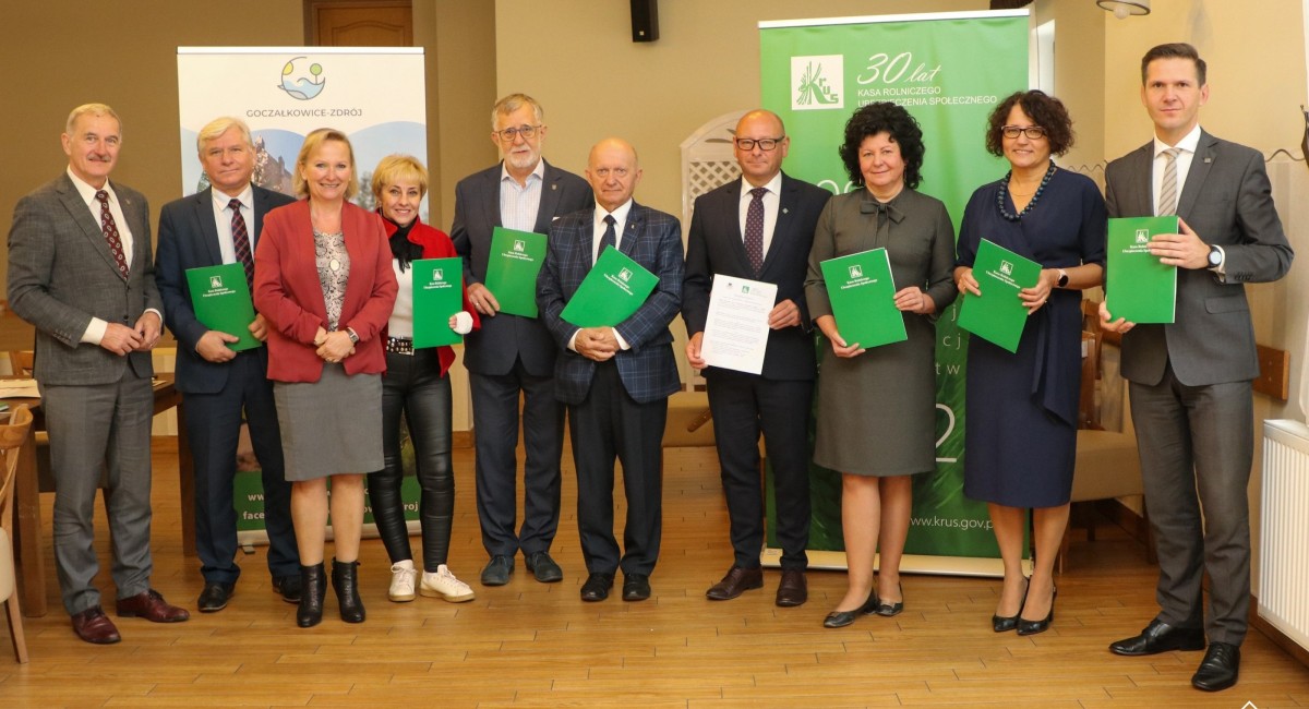 W sali posiedzeń urzędu w goczałkowicach stoją obok siebie wójtowie, burmistrz oraz starosta, a także dyrektor KRUS. Trzymaja zielone teczki z podpisanymi porozumieniami.