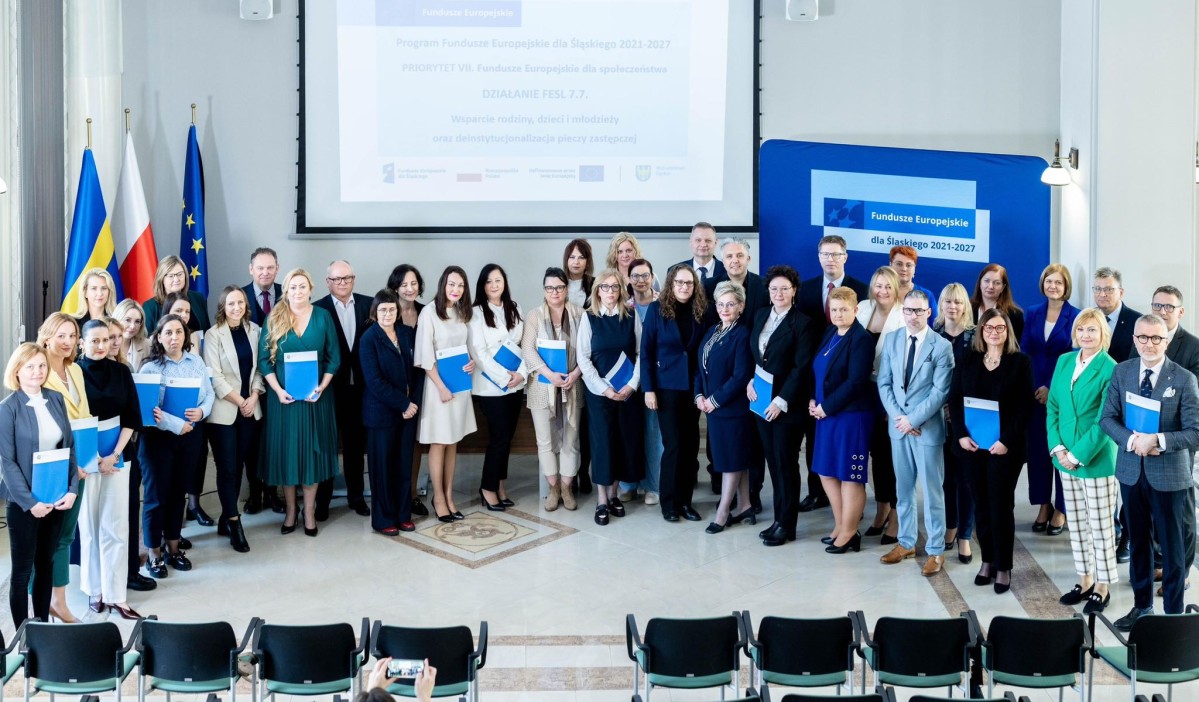 Grupa osób z teczkami, w którym znajdują się listy gratulacyjne.