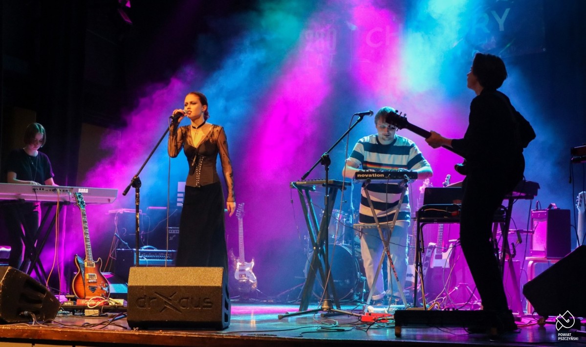 Grupa muzyków występuje na oświetlonej scenie.