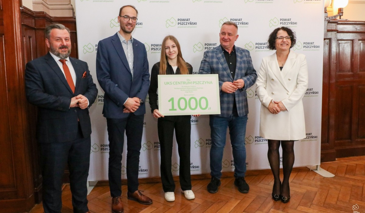 W sali sesyjnej starostwa na tle ścianki z logo powiatu stoją przedstawiciele klubu siatkówki, starosta i przewodniczący Rady
