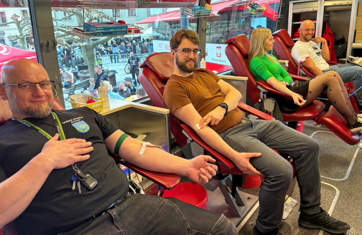 W ambulansie do poboru krwi trzech mężczyzn i kobieta oddaje krew