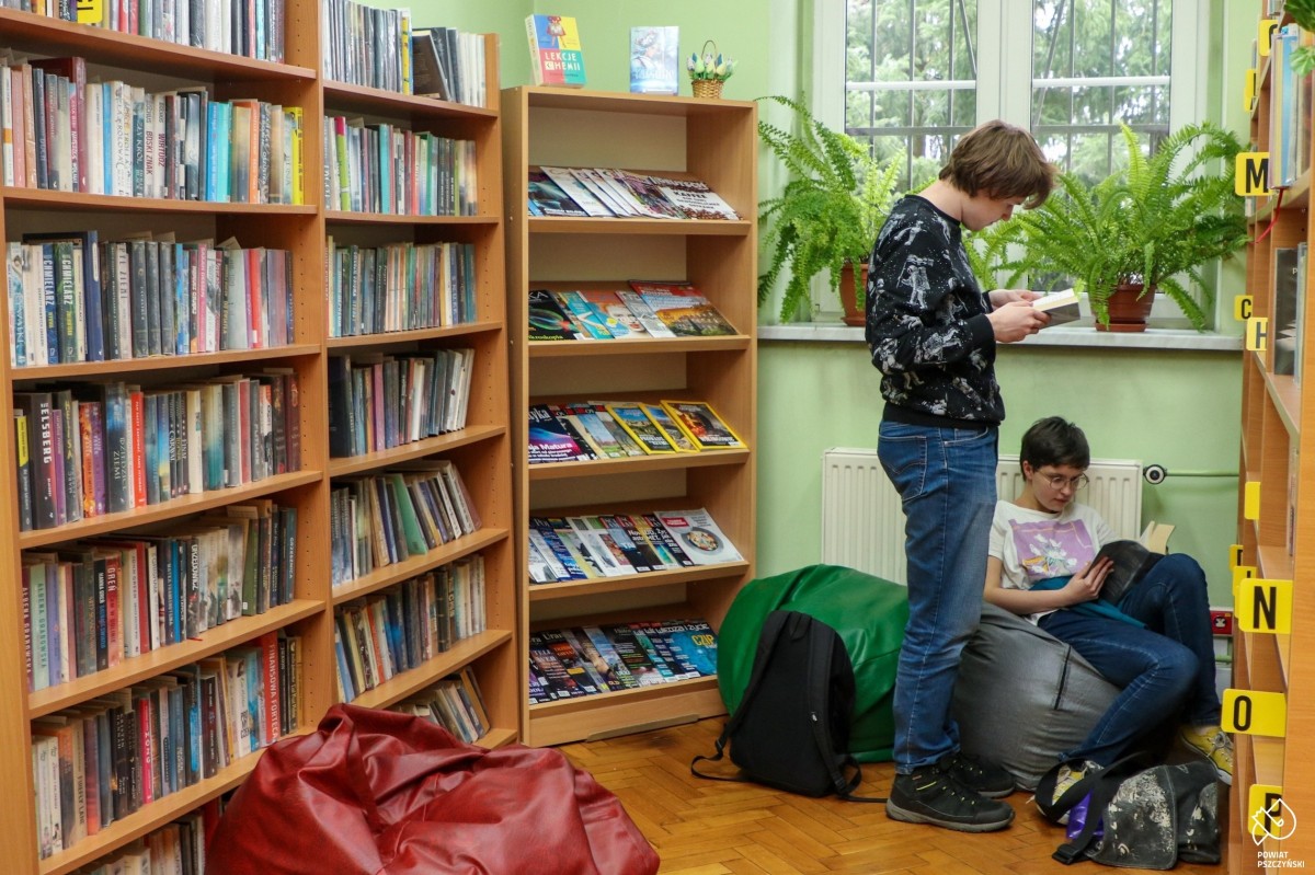 Uczniowie przeglądający książki w szkolnej bibliotece.