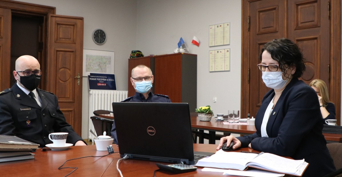 Trzy osoby siedzą przed komputerem podczas wideokonferencji.