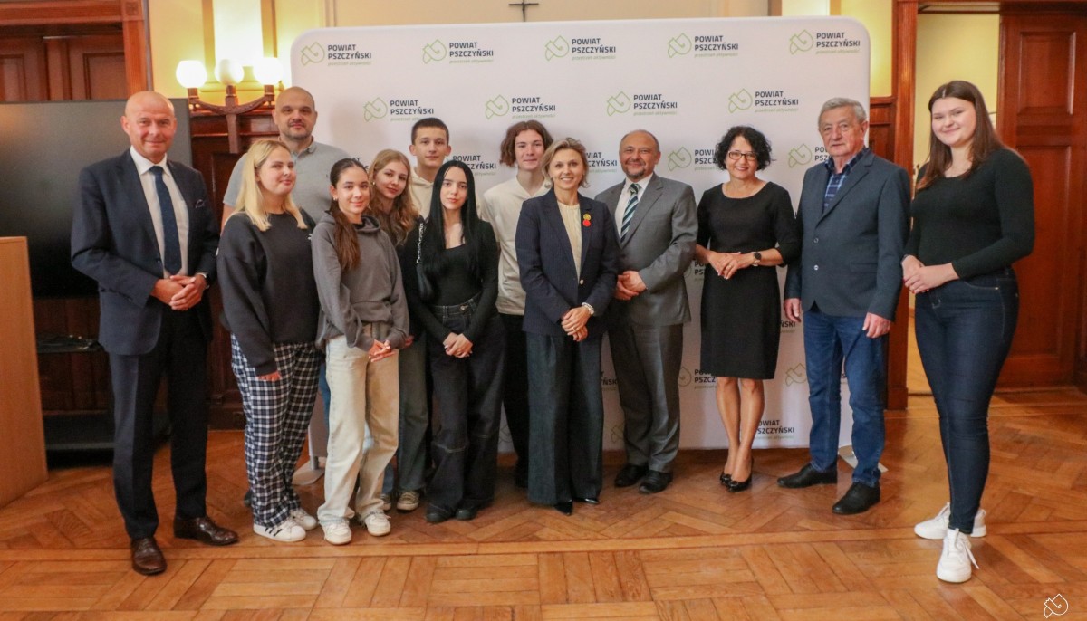 Grupa uczniów szkoły w Jastrzębiu, dwójka nauczycieli, starosta, wicestarosta i Kazimierz Tischner stoją w sali sesyjnej starostwa