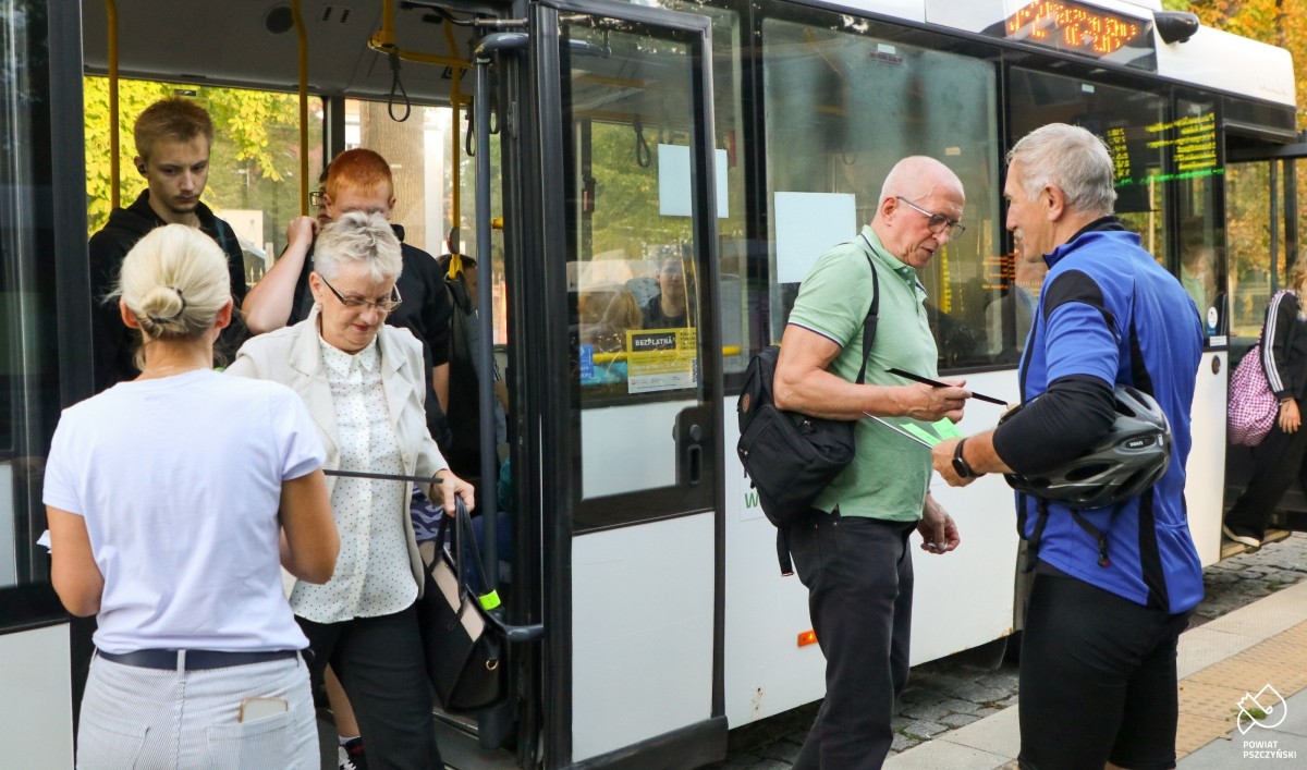 pasażerom wysiadający z autobusu wręczane są opaski odblaskowe