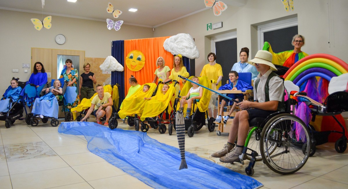 Uczestnicy DOREW podczas występu, kolorowa scena, uczestnicy teatrzyku w kolorowych strojach.